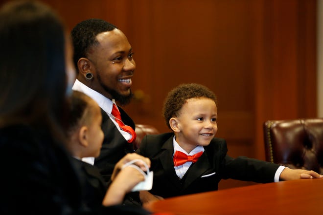Robert Carter smiles with his five new children during an adoption day ceremony at the Hamilton County Probate Court in downtown Cincinnati on Friday, Oct. 30, 2020.