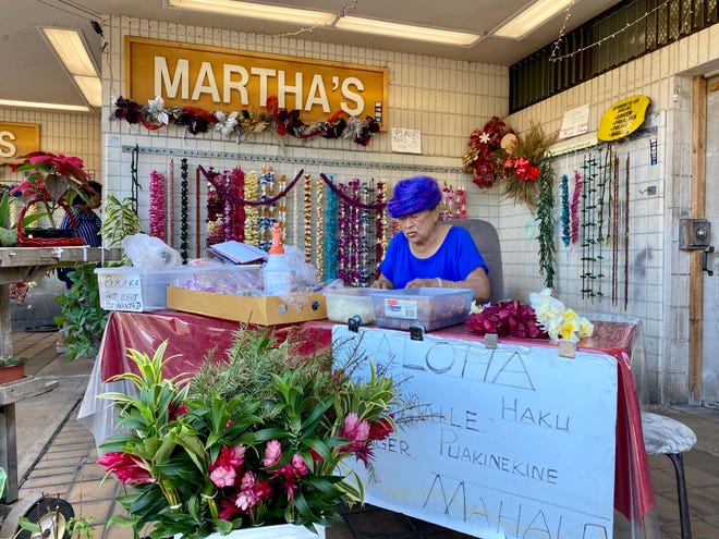 Milan Chun selects flowers for a lei as she waits for customers at her shop near Honolulu's Daniel K. Inouye International airport.