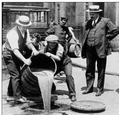 Law enforcement officials pour whiskey down the drain during Prohibition.