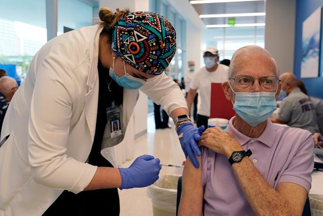 Dean Coleman, right, receives the Pfizer-BioNTech COVID-19 vaccine from graduate student Nina Cruz, left, on Wednesday at the Christine E. Lynn Rehabilitation Center at Jackson Hospital in Miami.