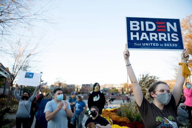 Eleanor Reilly, right, holds up a Biden Harris sign while cheering during an unofficial gathering to celebrate President Elect Joe Biden's win over incumbent President Donald Trump on Saturday, Nov. 7, 2020 at Washington Park in Over-The-Rhine.