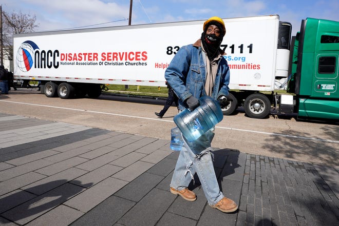 James White carries a bottle of donated water from a distribution site Thursday, Feb. 18, 2021, in Houston. Houston and several surrounding cities are under a boil water notice as many residents are still without running water in their homes.