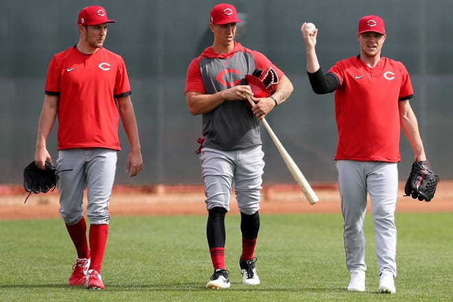 Cincinnati Reds starting pitcher Trevor Bauer (27) and relief pitcher Michael Lorenzen (21) listen to starting pitcher Sonny Gray (54) during spring practice, Friday, Feb. 21, 2020, at the baseball team's spring training facility in Goodyear, Ariz.