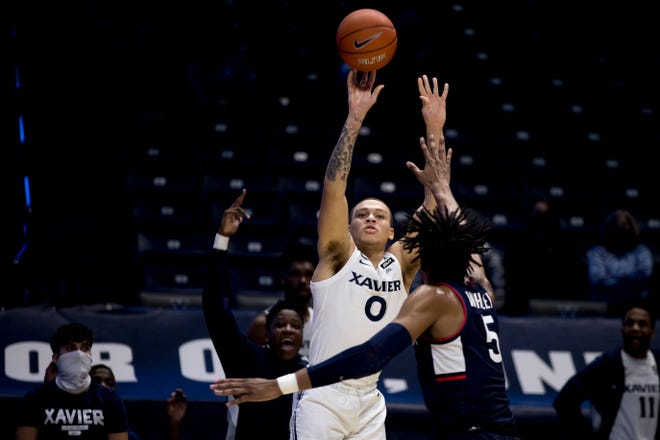 Xavier Musketeers guard C.J. Wilcher (0) shoots a 3-pointer over Connecticut Huskies forward Isaiah Whaley (5) in the second half of the NCAA men's basketball game on Saturday, Feb. 13, 2021, in Cincinnati. 
