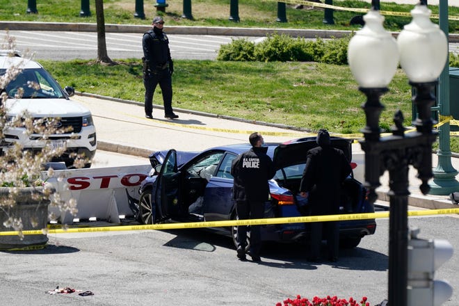 U.S. Capitol Police officers stand near a car that crashed into a barrier on Capitol Hill in Washington, Friday, April 2, 2021. 