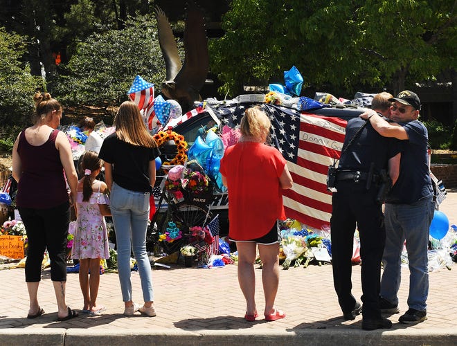 Pat Nevin, right, who said two of his three children work in law enforcement, hugs Arvada Police Officer Shaun Granmoe outside a memorial for Arvada Police Officer Gordon Beesley on June 22, 2021 in Arvada, Colo.