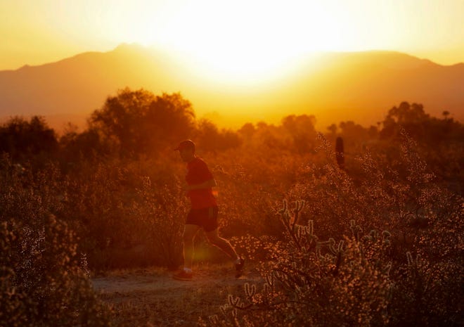 A man runs through the desert at sunrise in Phoenix on Friday. A record heat wave is rolling into Arizona, Nevada and California, threatening to bring 120-degree temperatures to Phoenix by early next week.