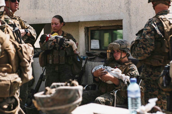 US Marines assigned to the 24th Marine Expeditionary Unit calm infants during an evacuation at Hamid Karzai International Airport in Kabul on August 20, 2021.