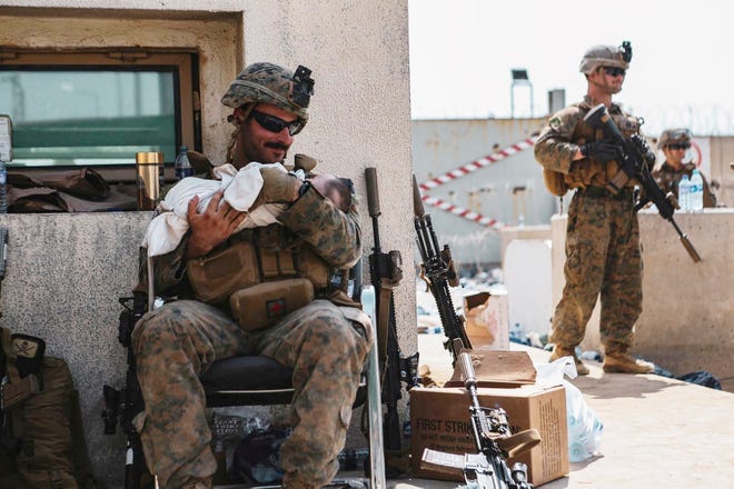 A U.S. Marine assigned to the 24th Marine Expeditionary Unit calms an infant during an evacuation at Hamid Karzai International Airport in Kabul on August 20, 2021.
