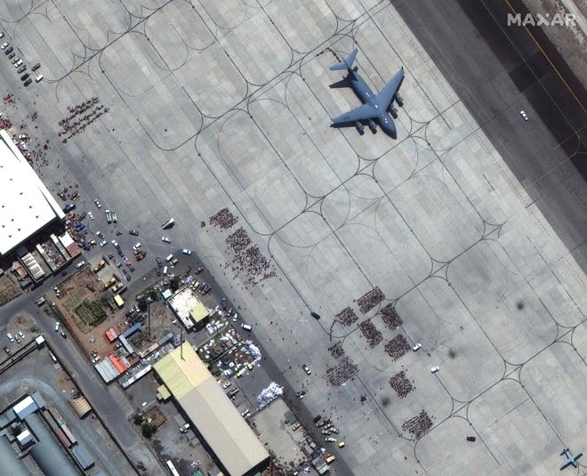 This handout satellite image released by Maxar Technologies shows crowds of people waiting on the tarmac at Kabul's Hamid Karzai International Airport in Afghanistan, with a C-17 transport aircraft ready, on Aug. 23, 2021.