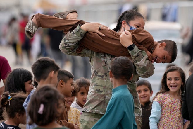 An U.S. soldier plays with recently evacuated Afghan children at the Ramstein U.S. Air Base, Germany, on Aug. 24, 2021.The largest American military community overseas housed thousands Afghan evacuees in an increasingly crowded tent city.