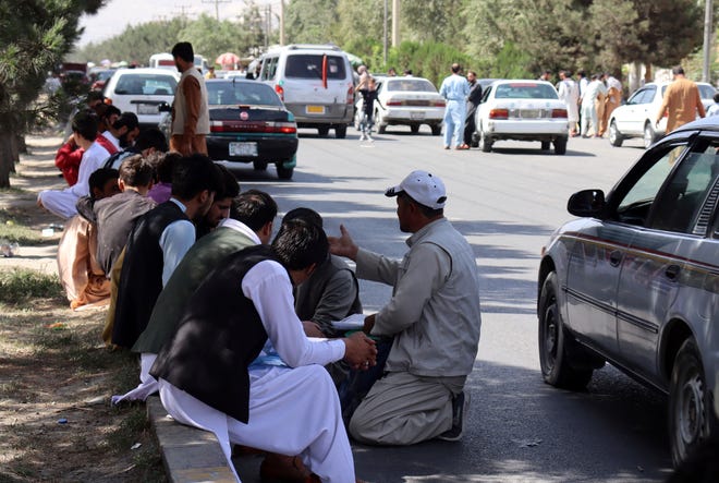Hundreds of people, some holding documents, gather near an evacuation control checkpoint on the perimeter of the Hamid Karzai International Airport, in Kabul, Afghanistan, on Aug. 27, 2021.