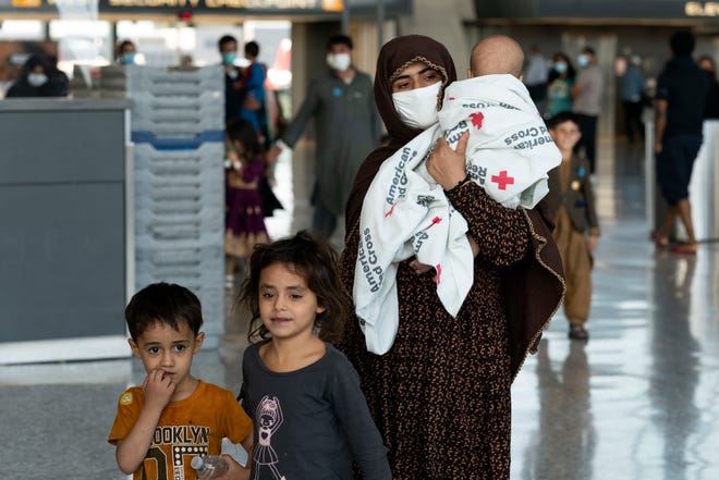 Families evacuated from Kabul, Afghanistan, walk through the terminal before boarding a bus after they arrived at Washington Dulles International Airport, in Chantilly, Virginia, on Aug. 27, 2021.