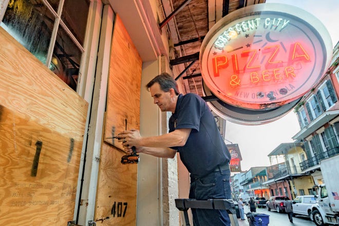 Michael Richard boards up Crescent City Pizza on Bourbon Street in New Orleans' French Quarter before landfall of Hurricane Ida on Aug. 28, 2021.