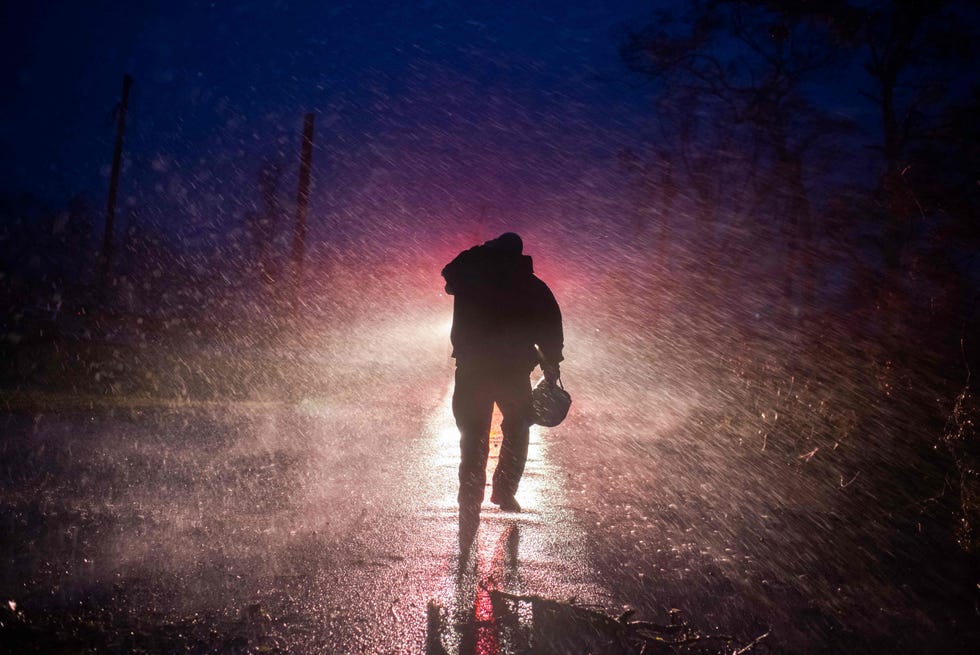 Montegut fire chief Toby Henry walks back to his fire truck in the rain as firefighters cut through trees on the road in Bourg, Louisiana as Hurricane Ida passes on August 29, 2021.