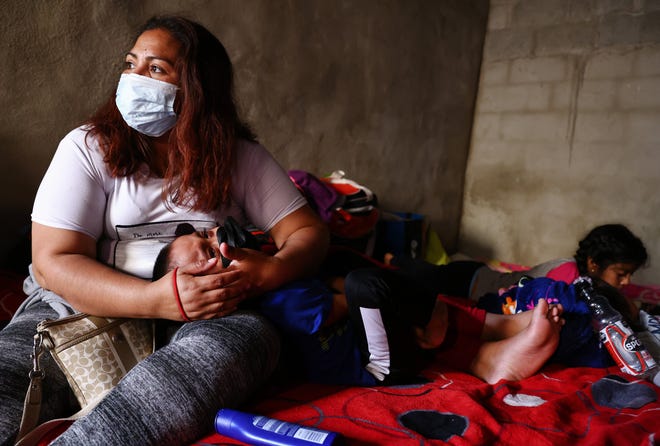 A mother holds her child as asylum-seeking migrants rest in a migrant shelter on July 21, 2021 in Tijuana, Mexico.
