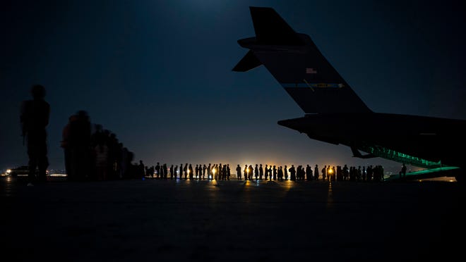 In this image provided by the U.S. Air Force and distributed by AP, U.S. Air Force aircrew, assigned to the 816th Expeditionary Airlift Squadron, prepare to load qualified evacuees aboard a U.S. Air Force C-17 Globemaster III aircraft in support of the Afghanistan evacuation at Hamid Karzai International Airport in Kabul, Afghanistan, on Aug. 21, 2021.