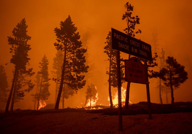 Fire burns bright behind a Pacific Crest Tail sign on Echo Summit southwest of South Lake Tahoe, Calif., on Monday, Aug. 30, 2021. 