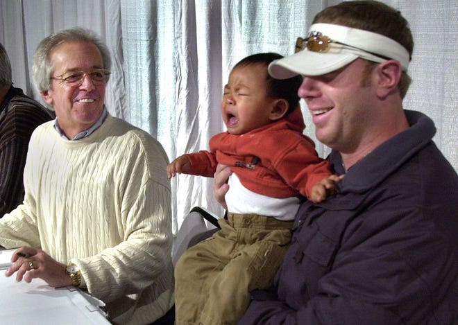 JANUARY 25, 2002: Adam Dunn holds Ethan Daniels, 15 months, of Lima, Ohio while they pose for a photo for Ethan's parents, although the boy was a little cranky. Marty Brennaman smiles next to them at a stop in Lima, Ohio, as a small group of the Cincinnati Reds headed out on a tour bus for a three state trip.