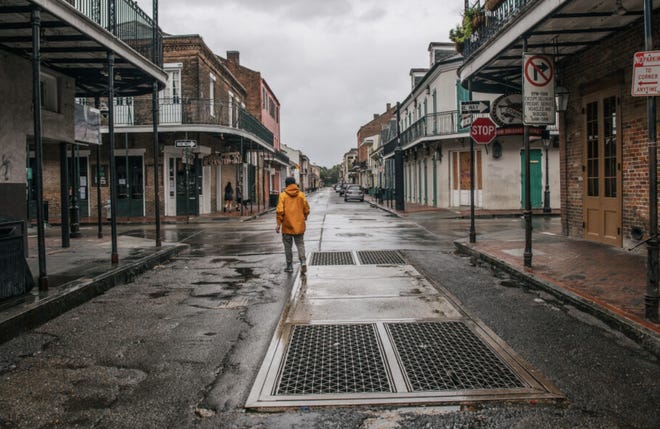 A person walks through New Orleans' French Quarter ahead of Hurricane Ida. Residents of New Orleans prepare as the outer bands of the hurricane begin to cut across the city.