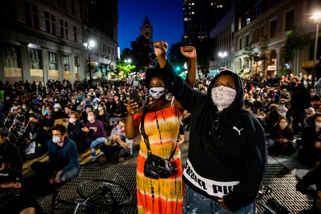 Demonstrators raise their fists during a "Sit Out the Curfew" protest in Oakland, California, on June 3, 2020, after the death of George Floyd, who was murdered in Minneapolis while in police custody. It was the ninth straight night of protests around the country, with thousands chanting against racism and police brutality. (Photo by Philip Pacheco / AFP)