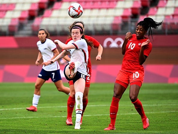 USA's midfielder Rose Lavelle clears the ball ahead of Canada's defender Ashley Lawrence (right) during the Tokyo 2020 Olympic Games women's semi-final football match between the United States and Canada at Ibaraki Kashima Stadium in Kashima on August 2, 2021.