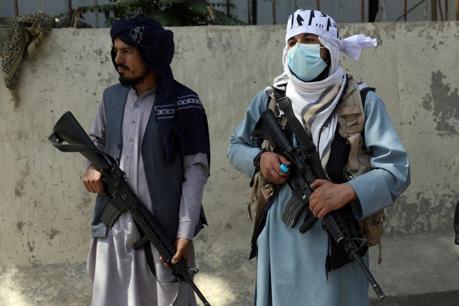 Taliban fighters stand guard in the main gate leading to Afghan presidential palace, in Kabul, Afghanistan, Monday, Aug. 16, 2021. The U.S. military struggled to manage a chaotic evacuation from Afghanistan on Monday as the Taliban patrolled the capital and tried to project calm after toppling the Western-backed government.