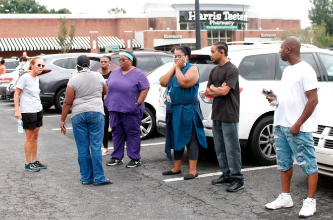 Anxious parents stand in the parking lot of a shopping center in Winston-Salem, N.C., on Wednesday, Sept. 1, 2021. One student was killed in a shooting at a North Carolina high school Wednesday and authorities were looking for the suspect, officials said.