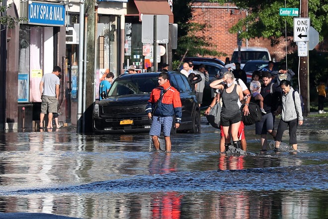 A family wades in the water as they evacuate along  Mamaroneck Avenue in Mamaroneck, N.Y., Sept. 2, 2021. Rains from Ida flooded the area overnight.