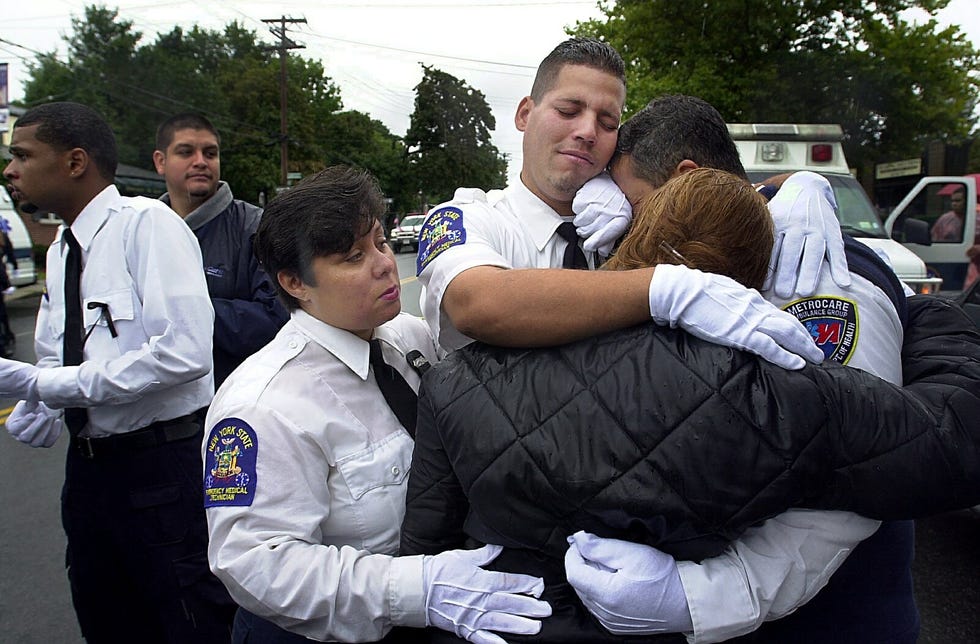 EMT's from MetroCare Ambulance and co-workers of Yamel Merino hug outside Sinatra Funeral Home on Sept. 14, 2001, after the service for Merino, the first MetroCare EMT to die in the line of duty. Merino's body was one of the first recovered at the World Trade Center, her funeral among the first in a long line of funerals stretching through that fall, that winter, that spring.