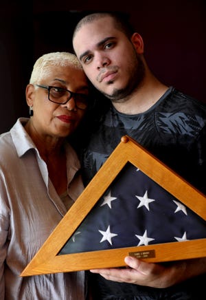 Kevin Villa, 28, and his grandmother, Ana Jager, hold the American flag that draped the coffin of his mother, Yamel Merino, in Jager's Yonkers home. Villa, who has spent most of his life talking about his mother's sacrifice, said he doesn't blame people for wondering what happened to the little boy in the yellow raincoat.