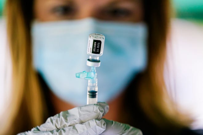 A nurse holds a syringe with the Pfizer-BioNTech COVID-19 vaccine at a vaccination clinic this week at the Reading Area Community College in Pennsylvania.