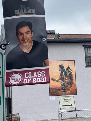 Native American student Javier Vallejo's senior portrait is hung in front of a painting of a Native American child representing the Canal Winchester mascot.
