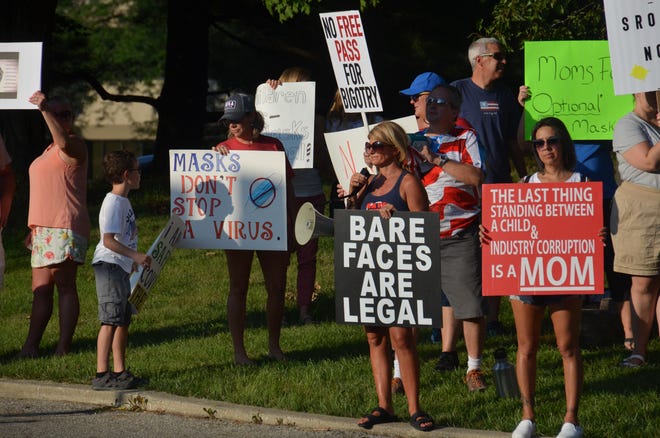Demonstrators opposed to a districtwide mask mandate in Worthington Schools hold signs outside the Worthington Education Center before the school board meeting Aug. 23.