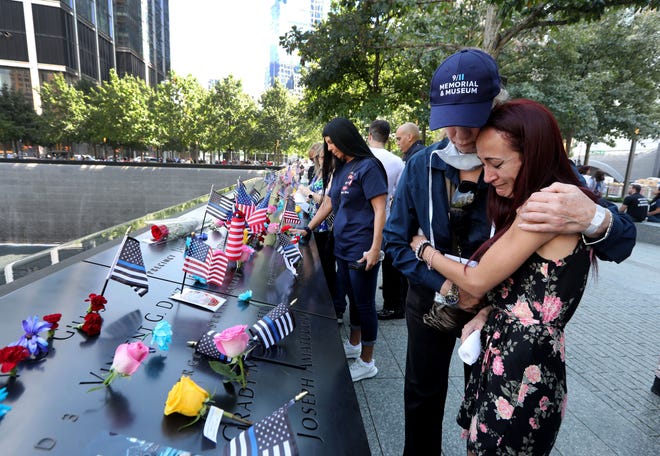Mercedes Arias, formerly of Yonkers, N.Y., is comforted by a 9/11 Museum staff member as she cries near the name of her father, Joseph Amatuccio at the 9/11 Memorial Sept. 11, 2021. Arias was attending the ceremony marking the 20th anniversary of the Sept. 11th attacks. Her father, who worked in the World Trade Center, died in the attacks.