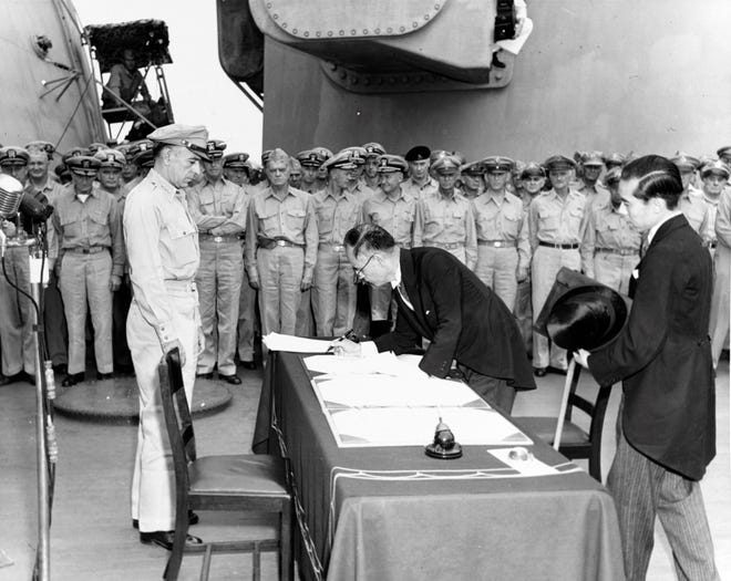 Japanese Foreign Minister Mamoru Shigemitsu signs the Instrument of Surrender on behalf of the Japanese Government, on board USS Missouri (BB-63), 2 September 1945. Lieutenant General Richard K. Sutherland, U.S. Army, watches from the opposite side of the table. Foreign Ministry representative Toshikazu Kase is assisting Mr. Shigemitsu.