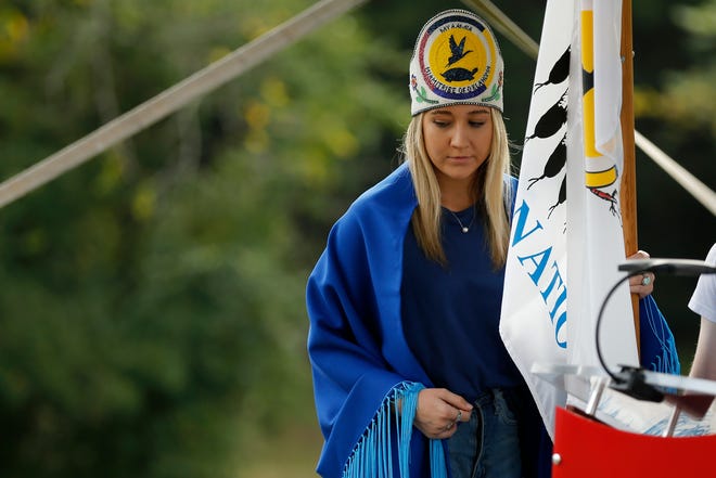 Grace Lankford, 20, a junior at Miami University, carries the flag of the Miami Tribe of Oklahoma during a Day of Reflection ceremony on the campus of Miami University in Oxford, Ohio, on Monday, Oct. 11, 2021. A ceremony was hosted to commemorate the 175th anniversary of the Myaamia Tribe that was forcibly removed from their land. 