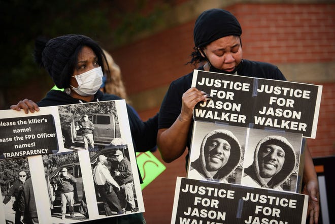 Pandora Harrington, right, cries as she holds a sign with an image of Jason Walker during a demonstration in Fayetteville, North Carolina.