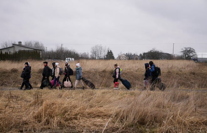 People walk with their belongings, as they flee Ukraine, at the border crossing in Medyka, Poland, Saturday, March 5, 2022.