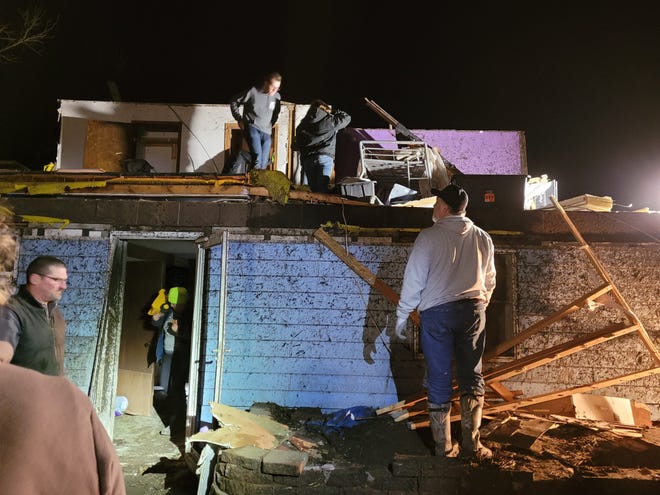 People removing belongings from their home after a tornado ripped through in Winterset, Iowa, on March 5, 2022.