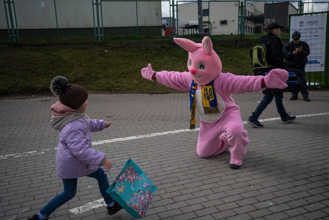 Performer Ben Dusing, from Fort Mitchell, Kentucky, wears an Easter rabbit costume as he prepares to embrace Lilia at the Medyka border crossing in Poland on April 17, 2022.